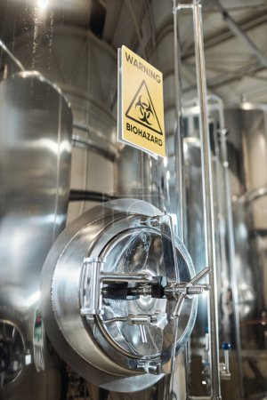 Téléchargez les photos : Image de fond verticale du panneau d'avertissement de danger biologique sur le réservoir de stockage en acier dans une usine chimique - en image libre de droit