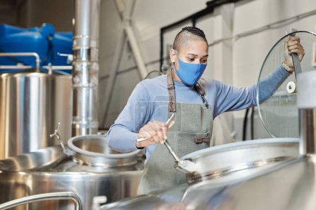 Téléchargez les photos : Portrait de travailleuse portant des réservoirs d'ouverture de masque à l'usine de fabrication de bière - en image libre de droit