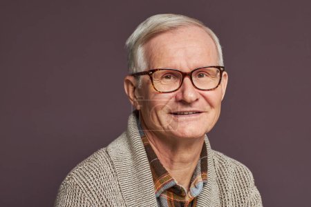 Foto de Retrato de hombre mayor con el pelo blanco en gafas sonriendo a la cámara sobre fondo gris - Imagen libre de derechos