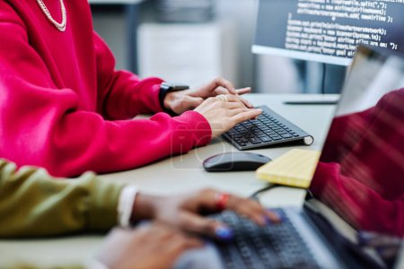 Photo for Close up of young person typing at computer keyboard while writing code in software development office, magenta accent - Royalty Free Image