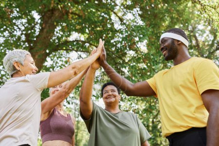 Photo for Low angle view at group of active senior women high five with male trainer after enjoying outdoor workout - Royalty Free Image