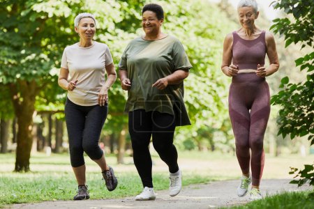 Téléchargez les photos : Portrait complet de trois femmes âgées actives faisant du jogging dans le parc ensemble et appréciant le sport - en image libre de droit