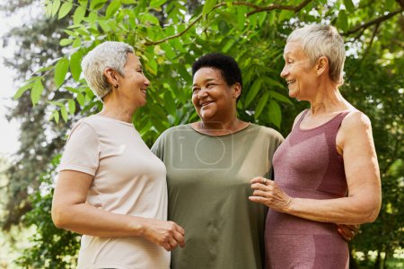 Foto de Retrato de la cintura hacia arriba de tres mujeres mayores activas sonriendo alegremente al aire libre - Imagen libre de derechos