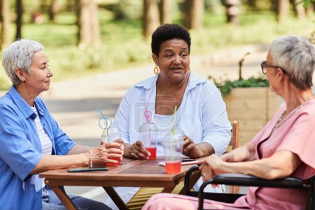 Foto de Diverso grupo de mujeres mayores disfrutando de bebidas en la cafetería al aire libre y charlando - Imagen libre de derechos