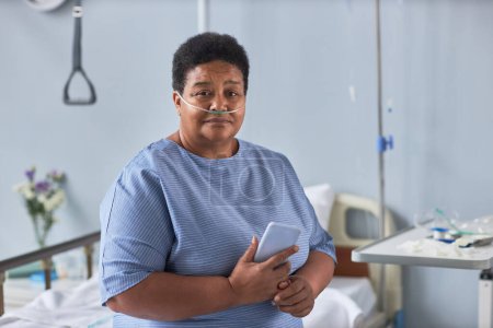 Foto de Retrato de una anciana negra sentada en la cama en la habitación del hospital con cánulas de oxígeno - Imagen libre de derechos