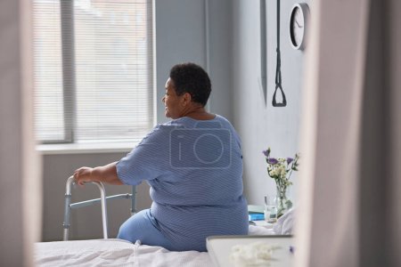 Téléchargez les photos : Vue arrière de la femme âgée solitaire dans la chambre d'hôpital, minime - en image libre de droit