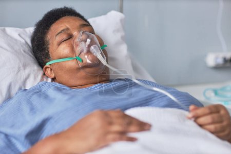 Foto de Mujer mayor negra durmiendo en la cama en la habitación del hospital con máscara de soporte de oxígeno - Imagen libre de derechos