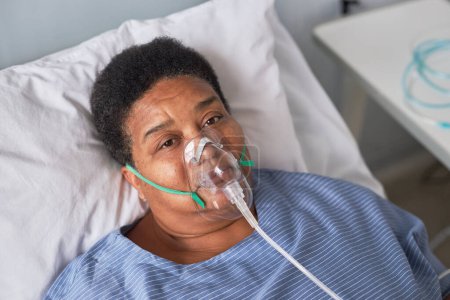 Téléchargez les photos : Portrait d'une femme âgée afro-américaine dans une chambre d'hôpital regardant une caméra, un support à oxygène - en image libre de droit