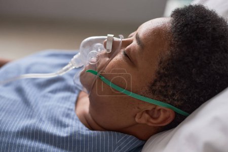 Foto de Vista lateral cercana de la mujer mayor negra con máscara de soporte de oxígeno en la habitación del hospital - Imagen libre de derechos
