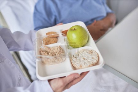 Photo for Close up of nurse holding healthy breakfast meal on tray and bringing in to patient in hospital - Royalty Free Image
