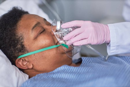 Foto de Primer plano de la enfermera colocando máscara de soporte de oxígeno en el paciente mayor en la habitación del hospital - Imagen libre de derechos
