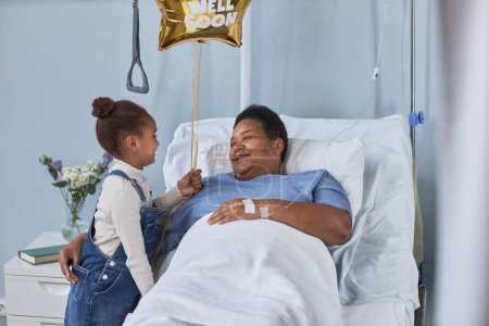 Foto de Retrato de una mujer mayor sonriente abrazando a una linda nieta en la habitación del hospital - Imagen libre de derechos