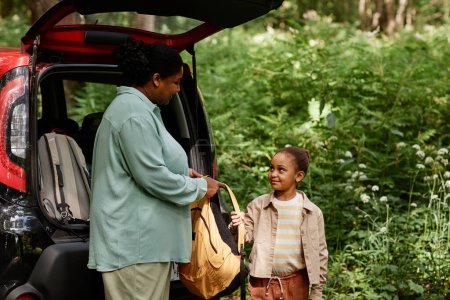Téléchargez les photos : Portrait latéral de mère et fille afro-américaine debout en voiture dans le sentier de la nature - en image libre de droit