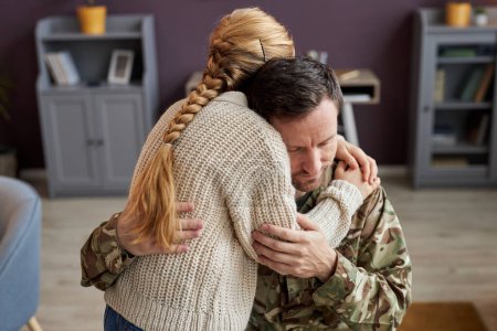 Foto de Retrato franco de una niña abrazando a un padre militar en casa en un momento de vinculación - Imagen libre de derechos