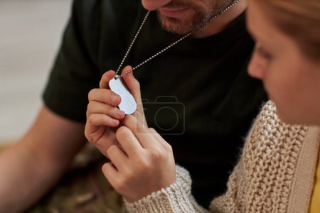 Téléchargez les photos : Gros plan de la fille qui regarde l'étiquette militaire sur le collier des pères, espace de copie - en image libre de droit