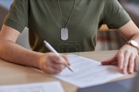 Téléchargez les photos : Gros plan d'une femme militaire méconnaissable signant un contrat au bureau, espace de copie - en image libre de droit