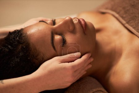 Foto de Mujer joven recibiendo masaje facial rejuvenecedor en salón de belleza - Imagen libre de derechos