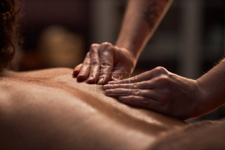 Téléchargez les photos : Masseuse utilisant la technique de pétrissage lors du massage du dos du client - en image libre de droit