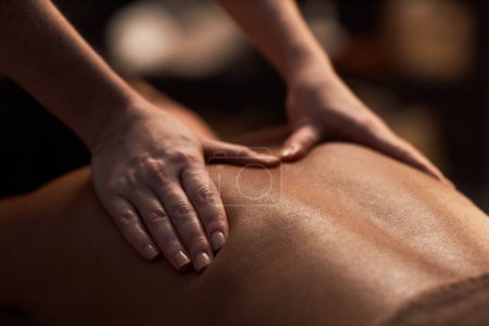 Foto de Imagen de primer plano del terapeuta de spa que aplica presión profunda al tejido al masajear la espalda de una mujer joven - Imagen libre de derechos