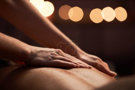 Photo for Closeup image of masseuse applying light strokes when applying oil on back of client - Royalty Free Image