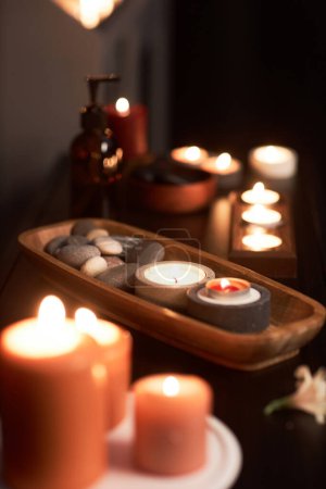 Téléchargez les photos : Bol en bois avec pierres et bougies allumées dans la salle de massage dans le salon de spa - en image libre de droit