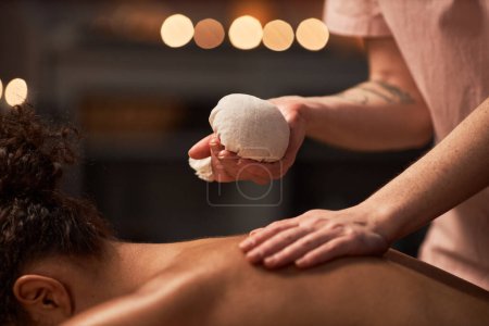 Photo for Young woman getting herbal bag massage to improve metabolism - Royalty Free Image