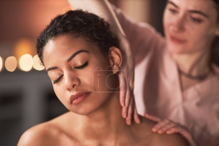 Téléchargez les photos : Masseuse à l'aide de longs mouvements lors du massage du cou de la jeune femme - en image libre de droit