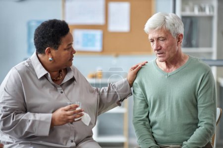 Photo for Portrait of black senior woman comforting depressed white haired man sharing stories in mental health support group - Royalty Free Image