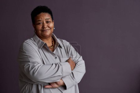 Photo for Minimal waist up portrait of black senior woman smiling at camera standing against purple background, copy space - Royalty Free Image
