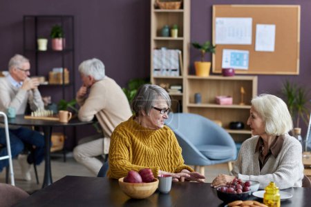 Téléchargez les photos : Groupe de personnes âgées profitant d'une conversation dans un espace commun confortable à la maison de retraite - en image libre de droit