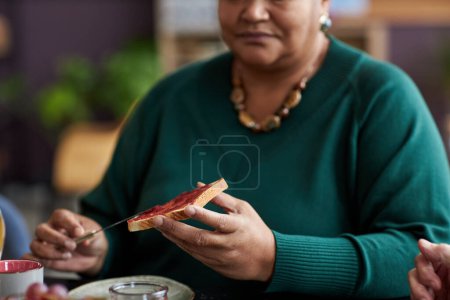 Téléchargez les photos : Gros plan de la femme âgée noire dégustant le petit déjeuner et faisant un sandwich à la gelée, espace de copie - en image libre de droit