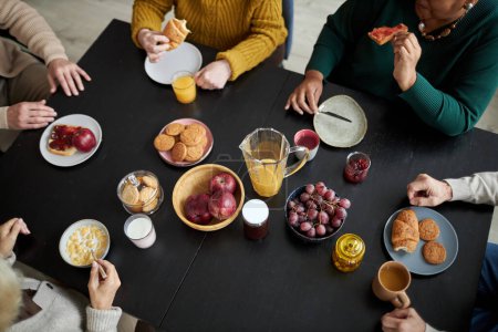 Photo for Top view at group of senior people enjoying breakfast sitting at table with food together in retirement home - Royalty Free Image