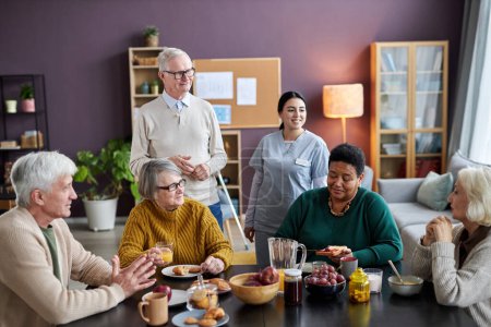 Téléchargez les photos : Scène de petit déjeuner dans une maison de retraite avec un groupe de personnes âgées souriantes - en image libre de droit
