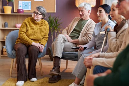 Téléchargez les photos : Vue d'ensemble du groupe de personnes âgées regardant ensemble la télévision dans une maison de retraite - en image libre de droit