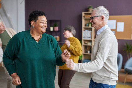 Téléchargez les photos : Portrait taille haute d'un couple de personnes âgées dansant dans une maison de retraite et profitant d'activités de groupe - en image libre de droit