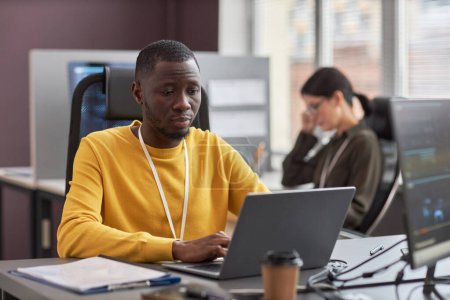 Foto de Retrato de hombre negro joven usando el ordenador portátil mientras trabajaba como desarrollador de software en la empresa de TI, espacio de copia - Imagen libre de derechos