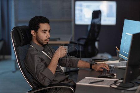 Téléchargez les photos : Portrait d'homme utilisant un ordinateur et buvant du café tout en travaillant dans un bureau de sécurité des données - en image libre de droit