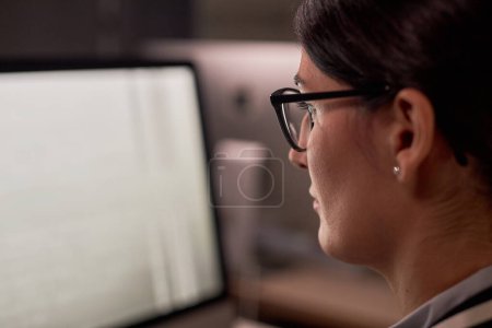 Foto de Primer plano de la mujer de negocios seria que usa el ordenador mientras trabaja por la noche en la oficina, espacio para copiar - Imagen libre de derechos
