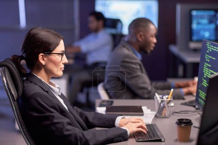 Foto de Retrato de vista lateral de una mujer de negocios seria que usa computadora en el lugar de trabajo en la oficina de seguridad de TI de alta tecnología - Imagen libre de derechos
