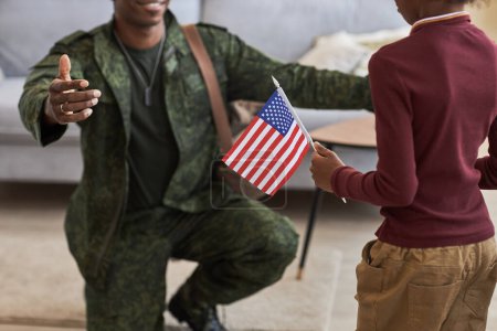 Téléchargez les photos : Gros plan de la petite fille avec le drapeau américain rencontrant son père militaire à la maison, il revient du service de guerre - en image libre de droit
