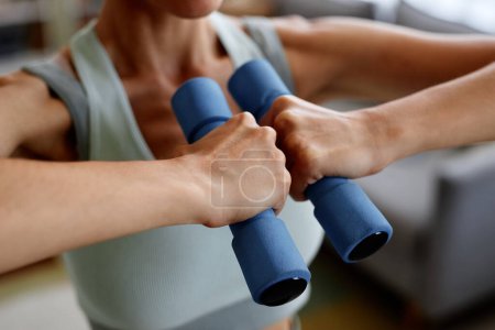 Photo for Closeup of unrecognizable woman holding dumbbells in strength training at home - Royalty Free Image