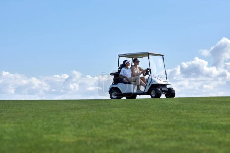Photo for Minimal background image of sporty couple driving golf cart across field with center line horizon, copy space - Royalty Free Image