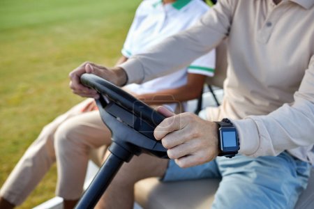 Photo for Close up of unrecognizable rich man driving golf cart with focus on hands holding wheel, copy space - Royalty Free Image