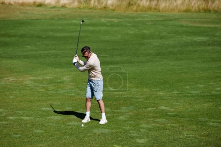 Téléchargez les photos : Vue grand angle à l'homme sportif jouant au golf sur le champ vert et club de golf oscillant avec précision, espace de copie - en image libre de droit