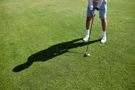 Téléchargez les photos : Section basse de l'homme méconnaissable jouant au golf sur l'herbe verte et visant un tir parfait, copier l'espace - en image libre de droit