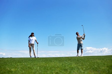 Téléchargez les photos : Portrait complet de couple sportif actif jouant au golf sur le terrain contre le ciel bleu, espace de copie - en image libre de droit