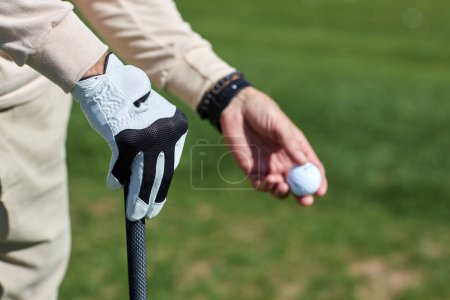 Téléchargez les photos : Gros plan de la main masculine tenant une balle de golf à l'extérieur contre l'herbe verte, espace de copie - en image libre de droit