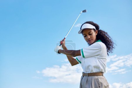 Foto de Retrato de ángulo bajo de una joven negra jugando al golf contra el cielo despejado, espacio para copiar - Imagen libre de derechos