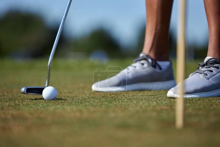 Foto de Primer plano de la persona irreconocible que juega al golf con el foco en el club de golf que golpea la bola en la hierba, espacio de copia - Imagen libre de derechos