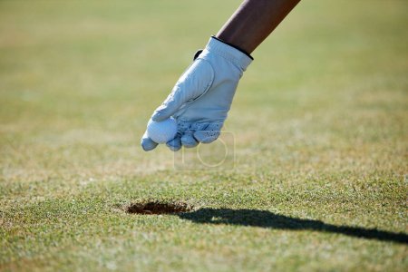 Téléchargez les photos : Gros plan de la main gantée ramassant la balle de golf du trou, espace de copie - en image libre de droit
